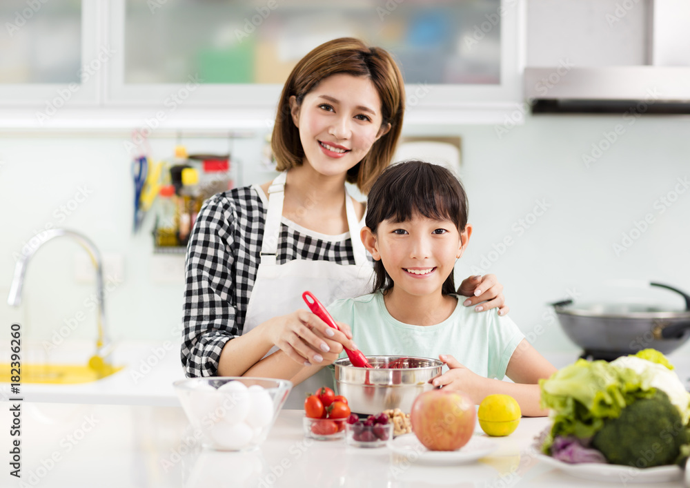 Happy mother and child in kitchen preparing cookies.