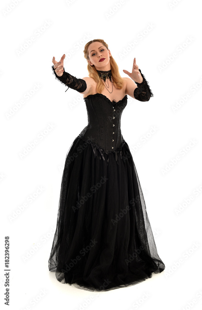 full length portrait of a blonde girl wearing black gothic gown. standing pose, isolated on white background. full length portrait of a blonde girl wearing black gothic gown. standing pose, isolated on white background.