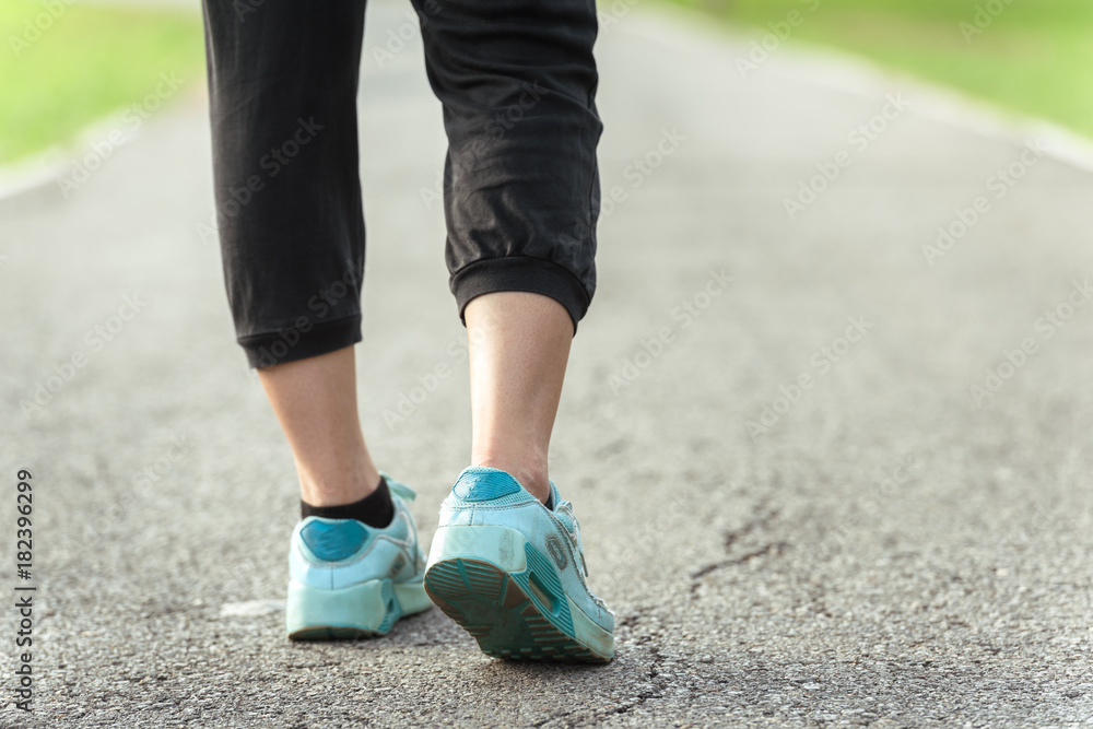Runner feet running on asphalt road in park - fitness sunrise jogging workout wellness concept Runner feet running on asphalt road in park - fitness sunrise jogging workout wellness concept