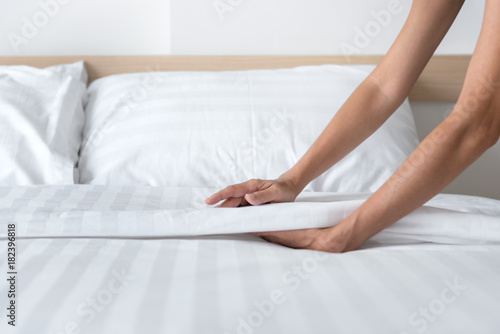 Hand set up white bed sheet in room