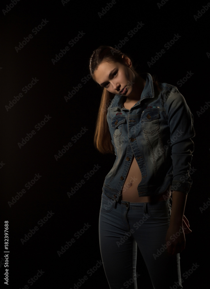 Amazing young woman in trendy outfit posing at black background
