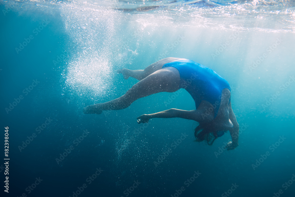 Fototapeta premium Woman swimming underwater in blue ocean, lifestyle
