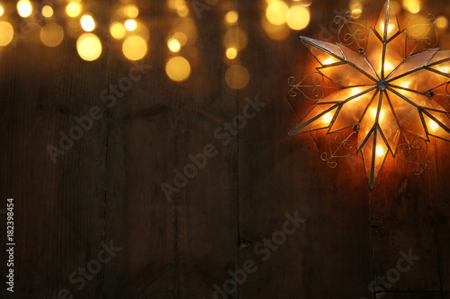 Image of christmas shining star over wooden background.