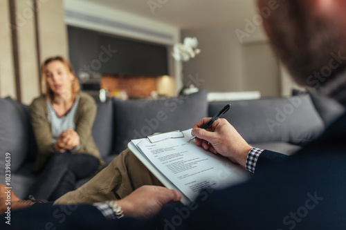 Photos Psychologist writing notes during a therapy session with patient
