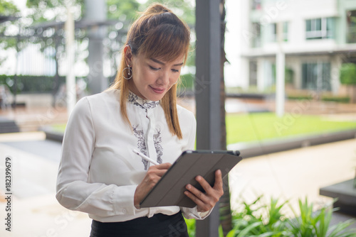 Elegant modern business woman working on tablet screen in an urban environment