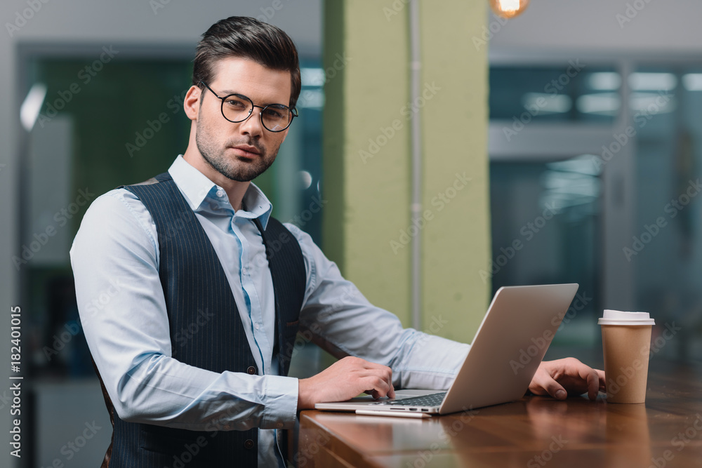 young businessman in eyeglasses working with laptop