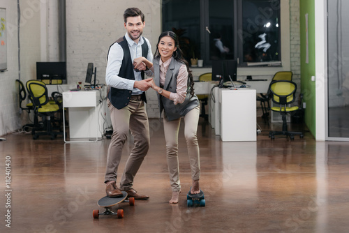 multiethnic businesspeople have fun with skateboards in office