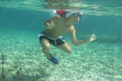 Boy in Santa hat swimming in sea