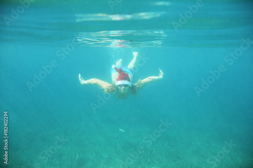Woman in Santa hat swimming underwater