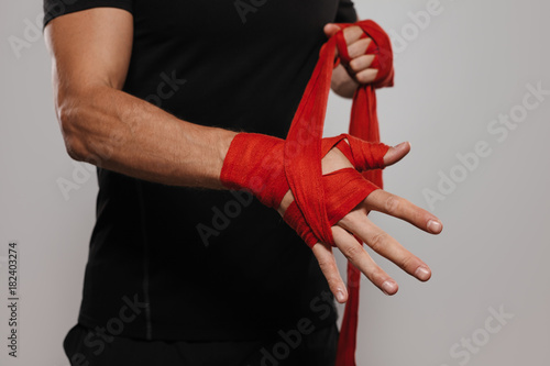 Crop man wrapping hands with band
