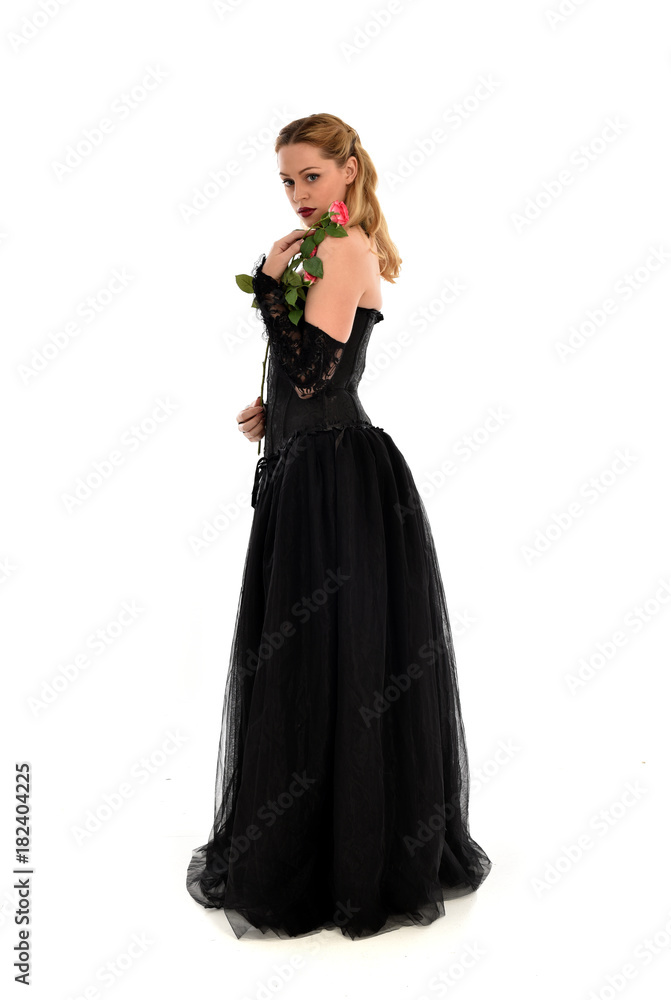 full length portrait of a blonde girl wearing black gothic gown. standing pose, isolated on white background.