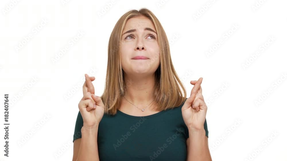 Portrait of concentrated woman dressed in green shirt willing good luck pleading with keeping fingers crossed beseeching god please over white background in studio. Concept of emotions Portrait of concentrated woman dressed in green shirt willing good luck pleading with keeping fingers crossed beseeching god please over white background in studio. Concept of emotions