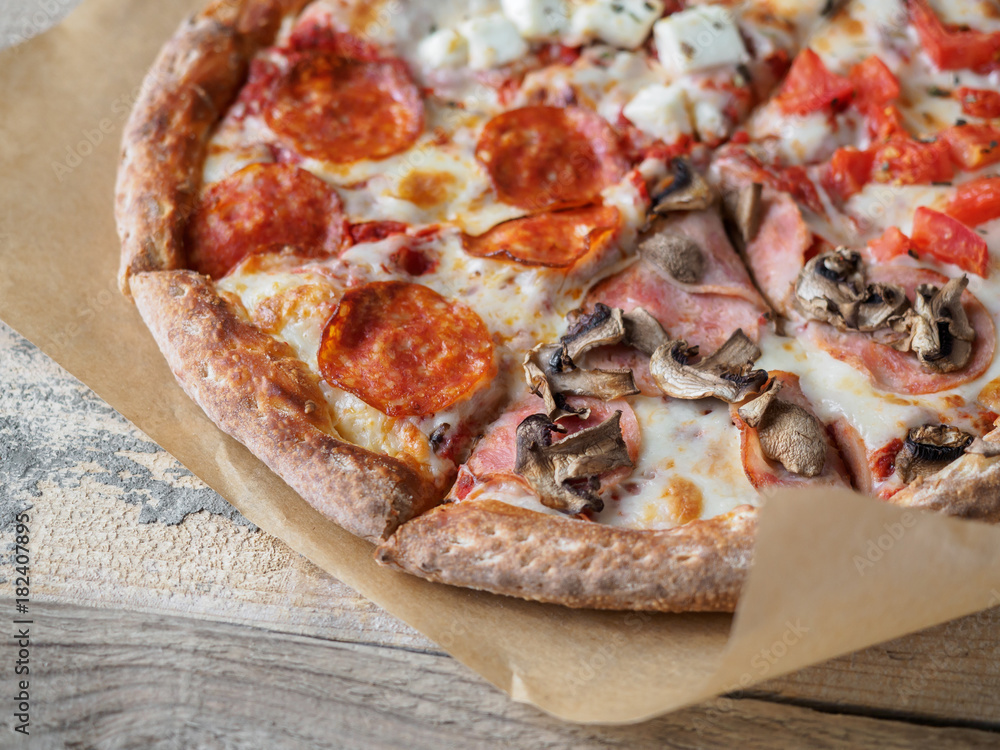 Homemade pizza set on paper at wooden table Homemade pizza set on paper at wooden table