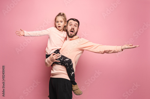 cheerful father playing with daughter on pink photo