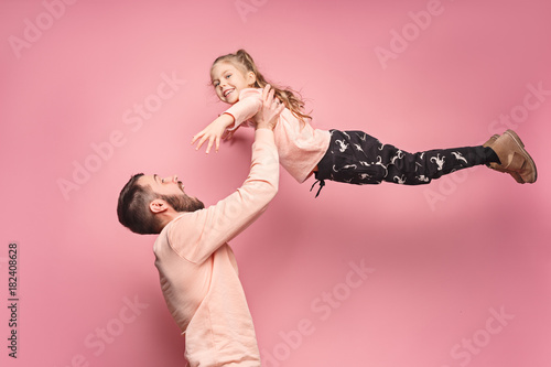 cheerful father playing with daughter on pink photo