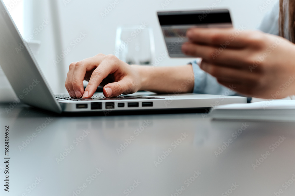 Close-up of female hand holding credit card and laptop making Internet purchase. Close-up of female hand holding credit card and laptop making Internet purchase.