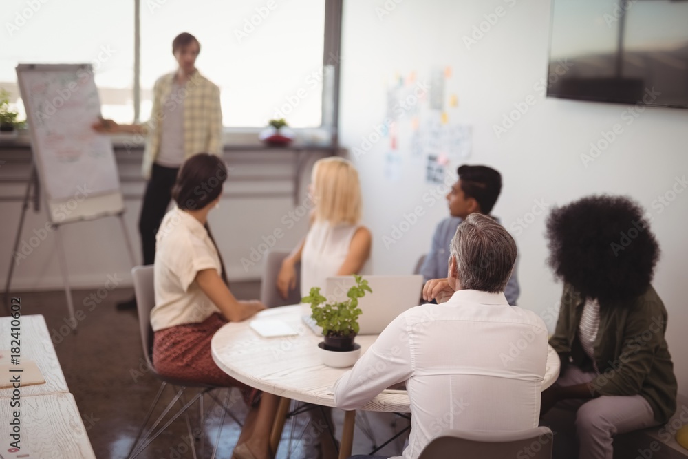 Colleagues looking at businessman giving presentation 