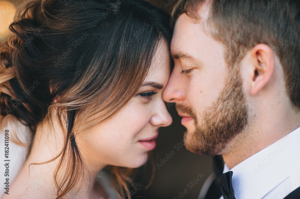 The faces of a man and a woman in profile during a tender kiss. Lovers are newlyweds. The faces of a man and a woman in profile during a tender kiss. Lovers are newlyweds.