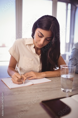 Businesswoman making notes during meeting in office