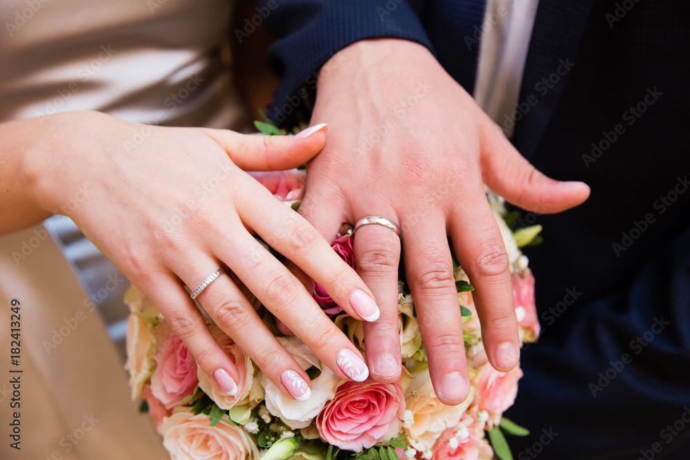 Fototapeta premium Bride and groom hands with wedding rings and beautiful bridal bouquet
