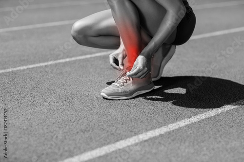 Low section of athlete tying shoelace on sports track