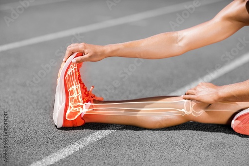 Low section of female athlete stretching on sports track
