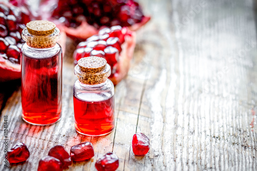 sliced pomegranate and extract in glass on wooden background