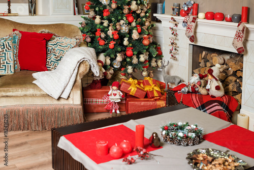 Cozyness and home comfort. Sofa near the decorated Christmas tree and fireplace with firewood. Winter holidays room interior, Christmas atmosphere.