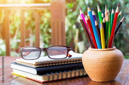 Assortment color pencil in pot and eyeglasses on stack book on rustic wooden table with copy space.  abstractartartistasiaassortmentbackgroundbrightclaycolorcolorfulcolumnistconceptcopydesigndrawdrawi
