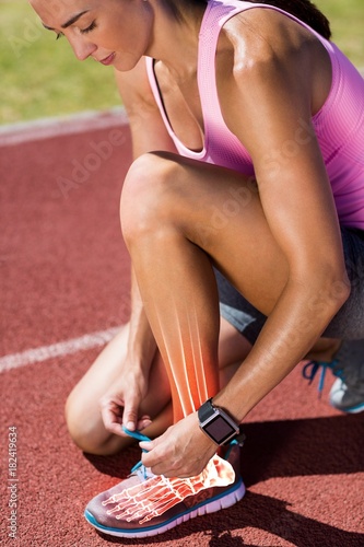 Highlighted bones of woman tying shoe lace on race track