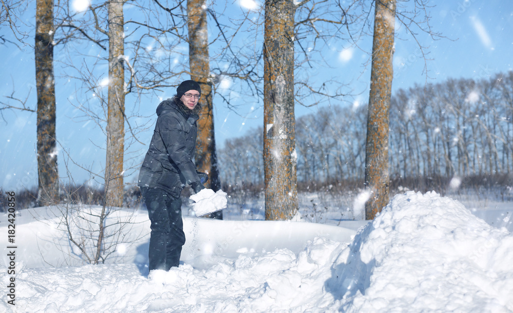 Naklejka premium man remove snow with shovel from the road in snowy winter 