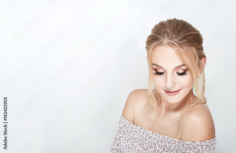 Close-up face of beautiful caucasian blonde woman with professional make-up and hairdo bun. Studio shot