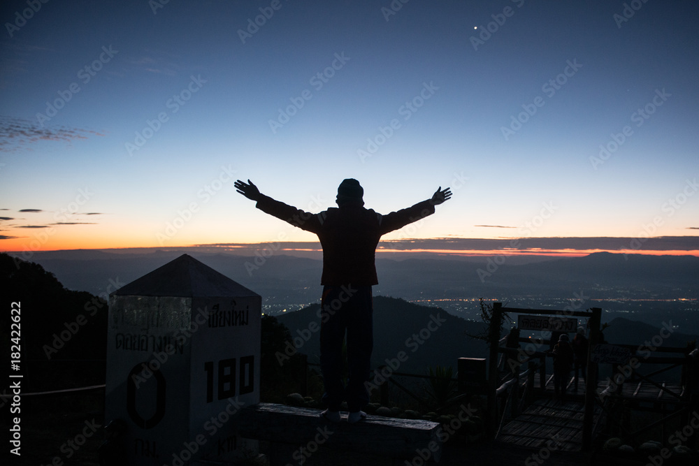 Fototapeta premium A person rising hand showing success on top of the mountain in the morning,