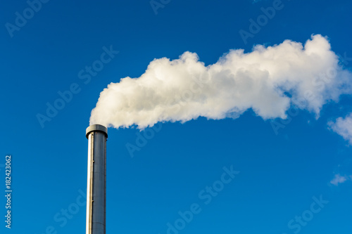 Papier peint A long cloud of white smoke escaping from a metallic chimney against a deep blue sky