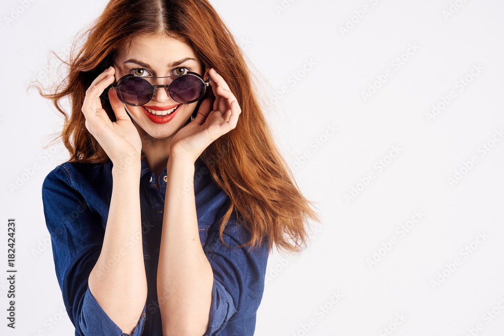 Naklejka premium Beautiful young woman holds on white isolated background in sunglasses