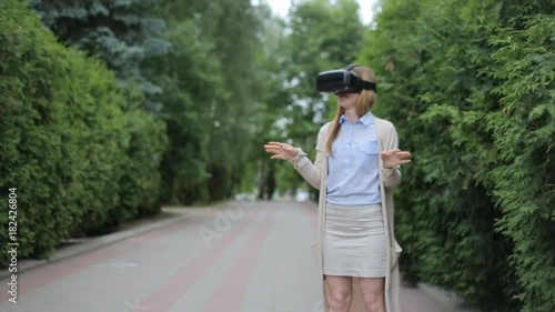 Young blonde woman playing game using VR-helmet for smart phones photo