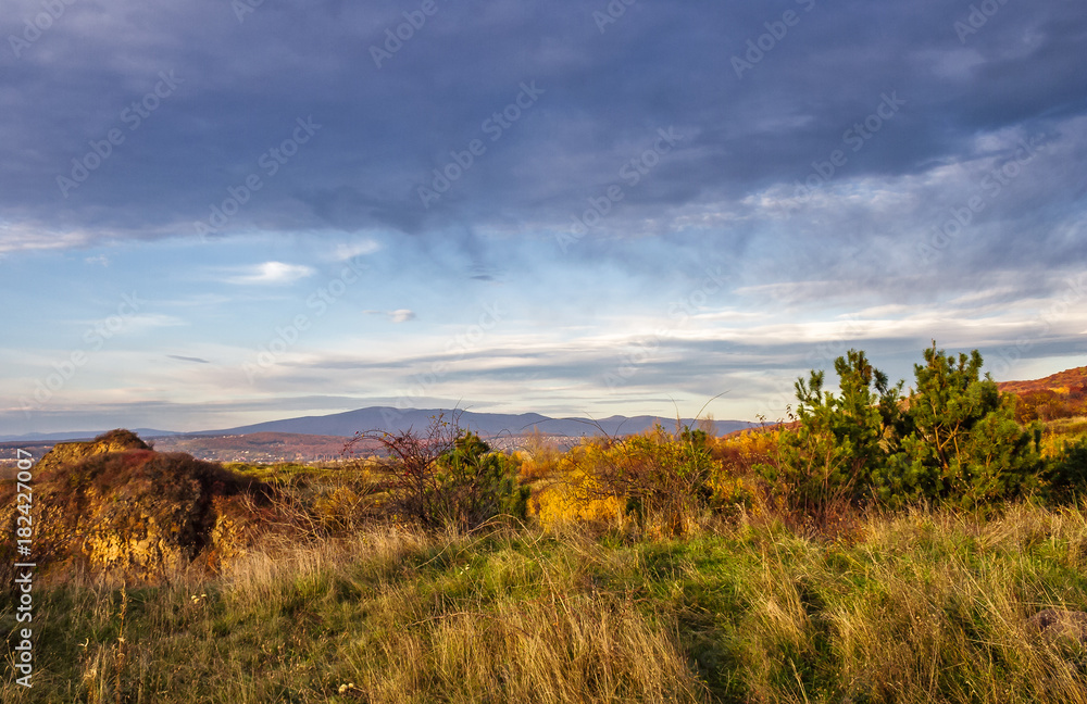 countryside with grassy hills at autumn sunset. beautiful mountainous landscape with heavy clouds on the sky