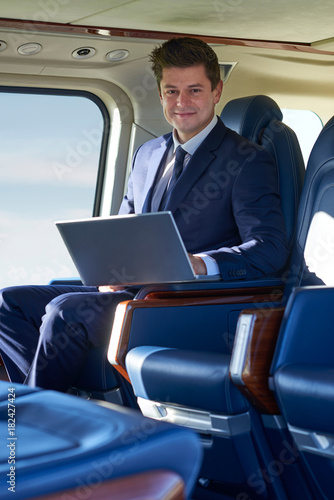Portrait Of Businessman Working On Laptop In Helicopter Cabin During Flight © highwaystarz