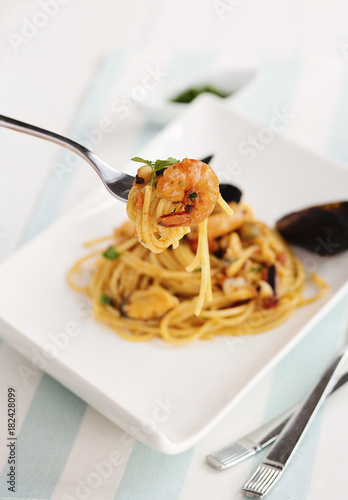 Spaghetti allo scoglio con pomodoro e frutti di mare. Piatto tipico della cucina italiana e mediterranea su sfondo chiaro