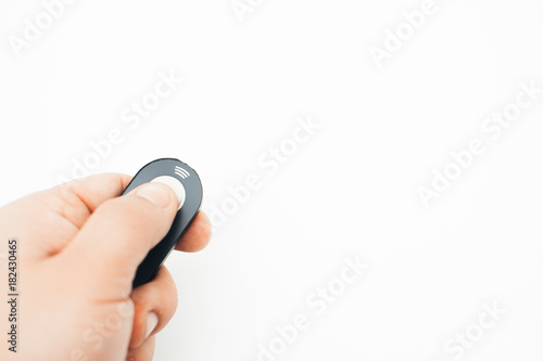 A small remote control in hand on white background from the camera, photo