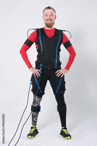 Red-haired man with a beard in electric muscular suit for stimulation
