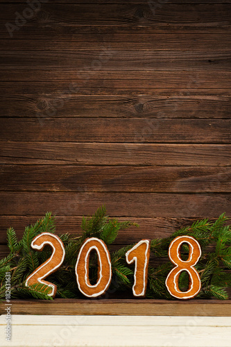 New Year's concept. Figure 2018 from gingerbread, fir branch on a wooden background, space for text. Vertical frame