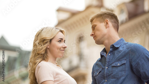 Young man seriously looking at girlfriend, woman late for date, apologetic look