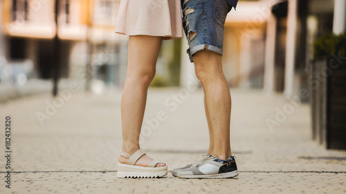 Legs of young man and woman standing close to each other, romantic relationship