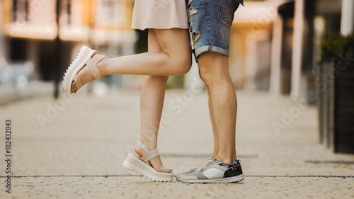 Legs of flirty girlfriend and boyfriend in love hugging and kissing in street
