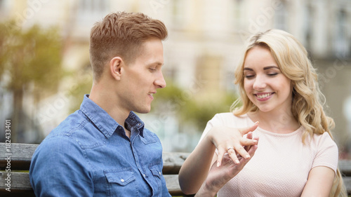 Excited young woman showing engagement ring on finger to beloved boyfriend