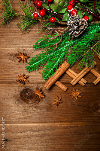 Branches green spruce with cones and toys and cinnamon sticks and star anise on a wooden background