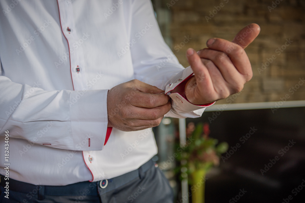 Obraz premium groom doing up his buttons on shirt sleeve 