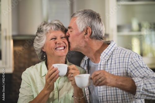 Senior man kissing wife while having coffee