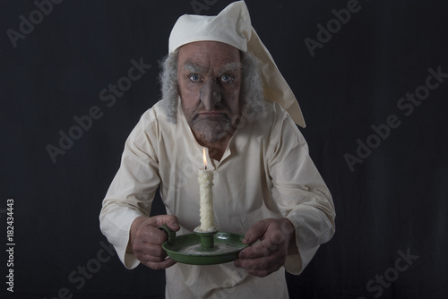 Photos Mature man in old fashioned Victorian night shirt holding a candle